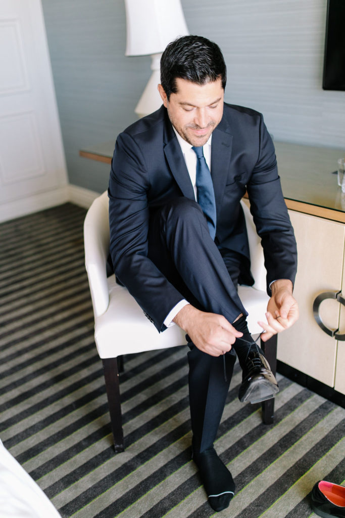 A glam and California infused wedding, groom getting ready wearing navy suit