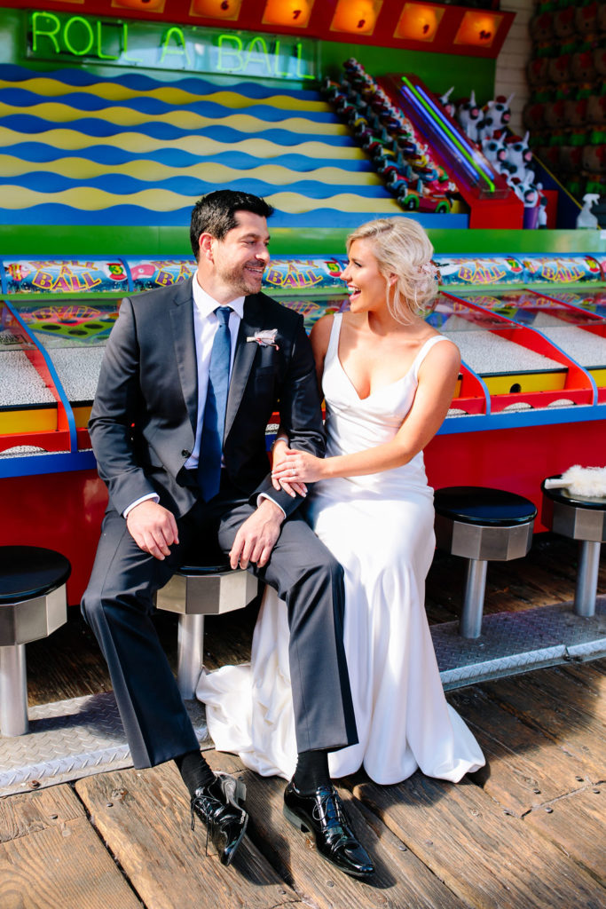 A glam and California infused wedding at Viceroy Santa Monica, bride and groom portrait shot in front of carnival games