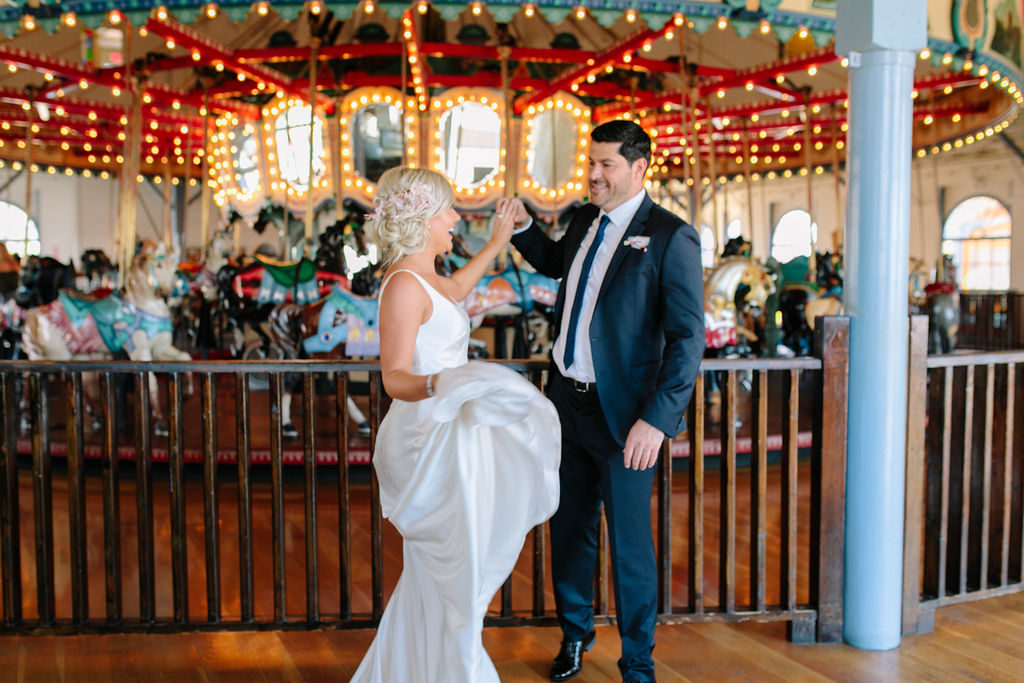 A glam and California infused wedding at Viceroy Santa Monica, bride and groom in front of carousel on Santa Monica pier