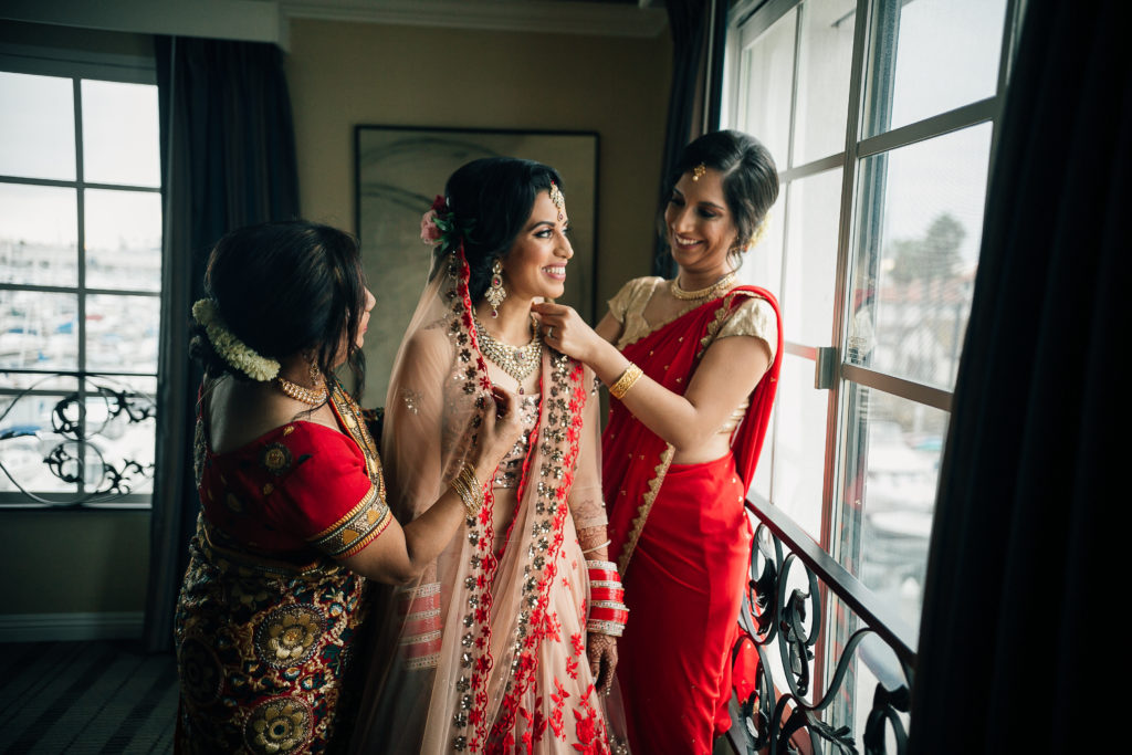 Stunning Indian Wedding in San Pedro, bride in gold and red wedding sari getting ready with mom and bridesmaid
