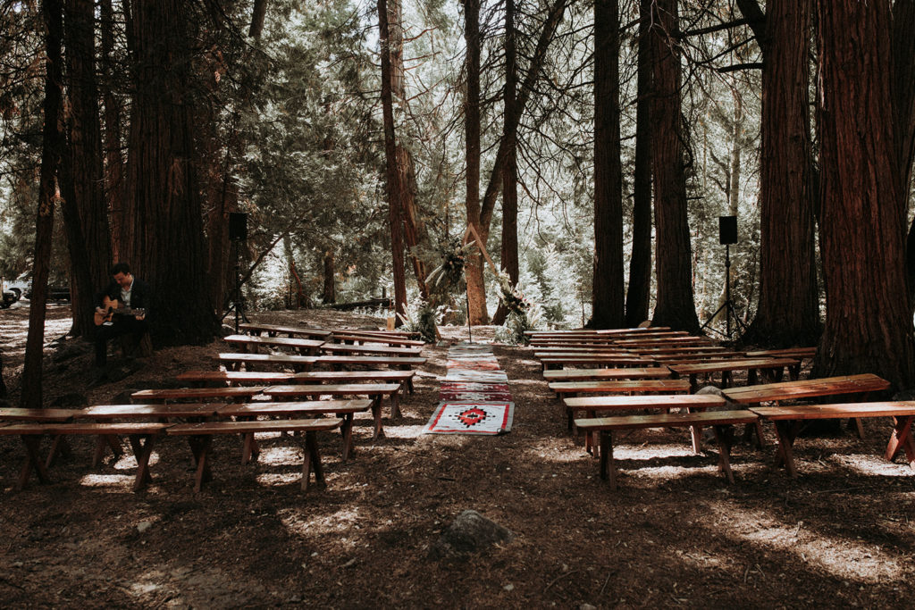Summer camp themed wedding in Big Bear at Camp Wasegan, forest wedding ceremony in the woods with mismatched oriental rugs and v shaped ceremony arch