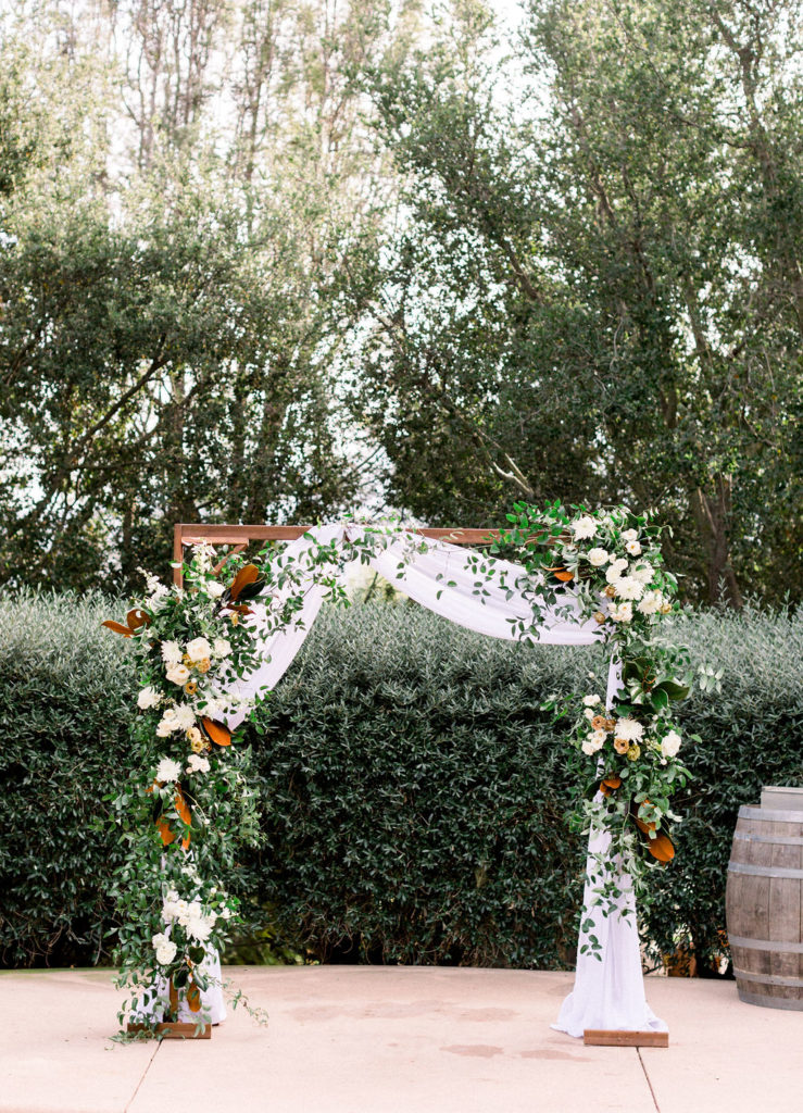 A Romantic Fall Wedding ceremony at Maravilla Gardens, ceremony arch with white flowers and drapery