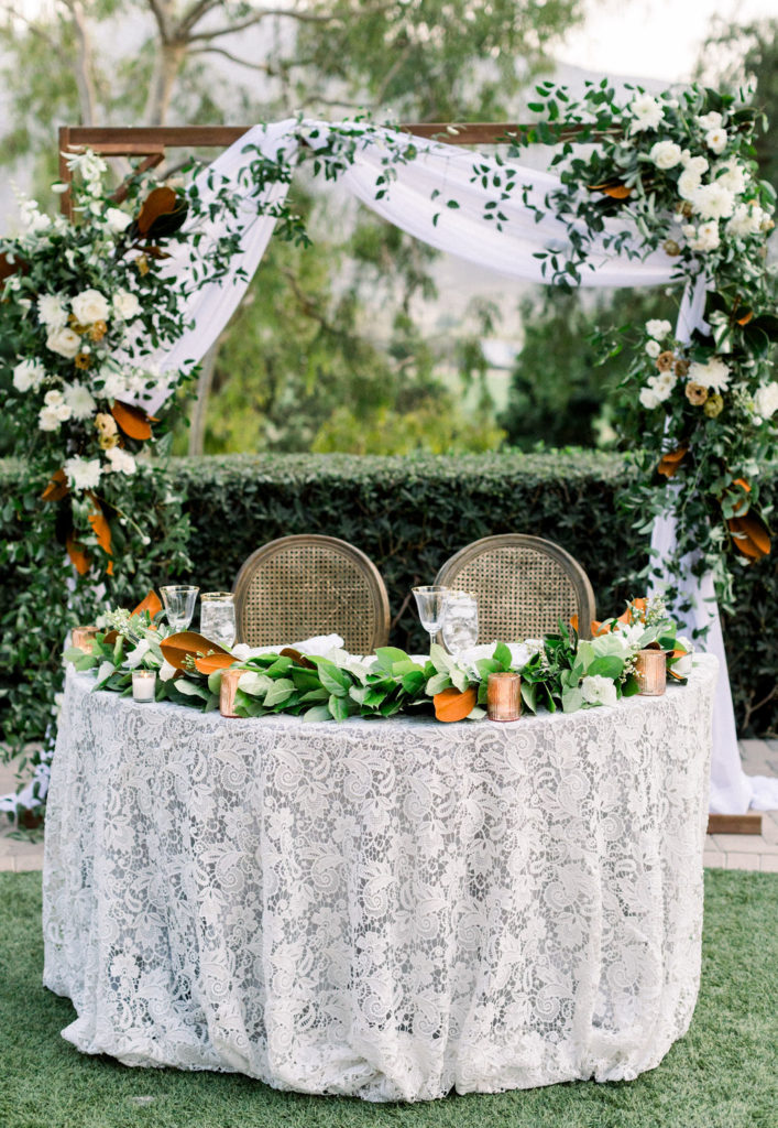 A Romantic Fall Wedding reception at Maravilla Gardens, sweetheart table with lace linen and magnolia leaf garland