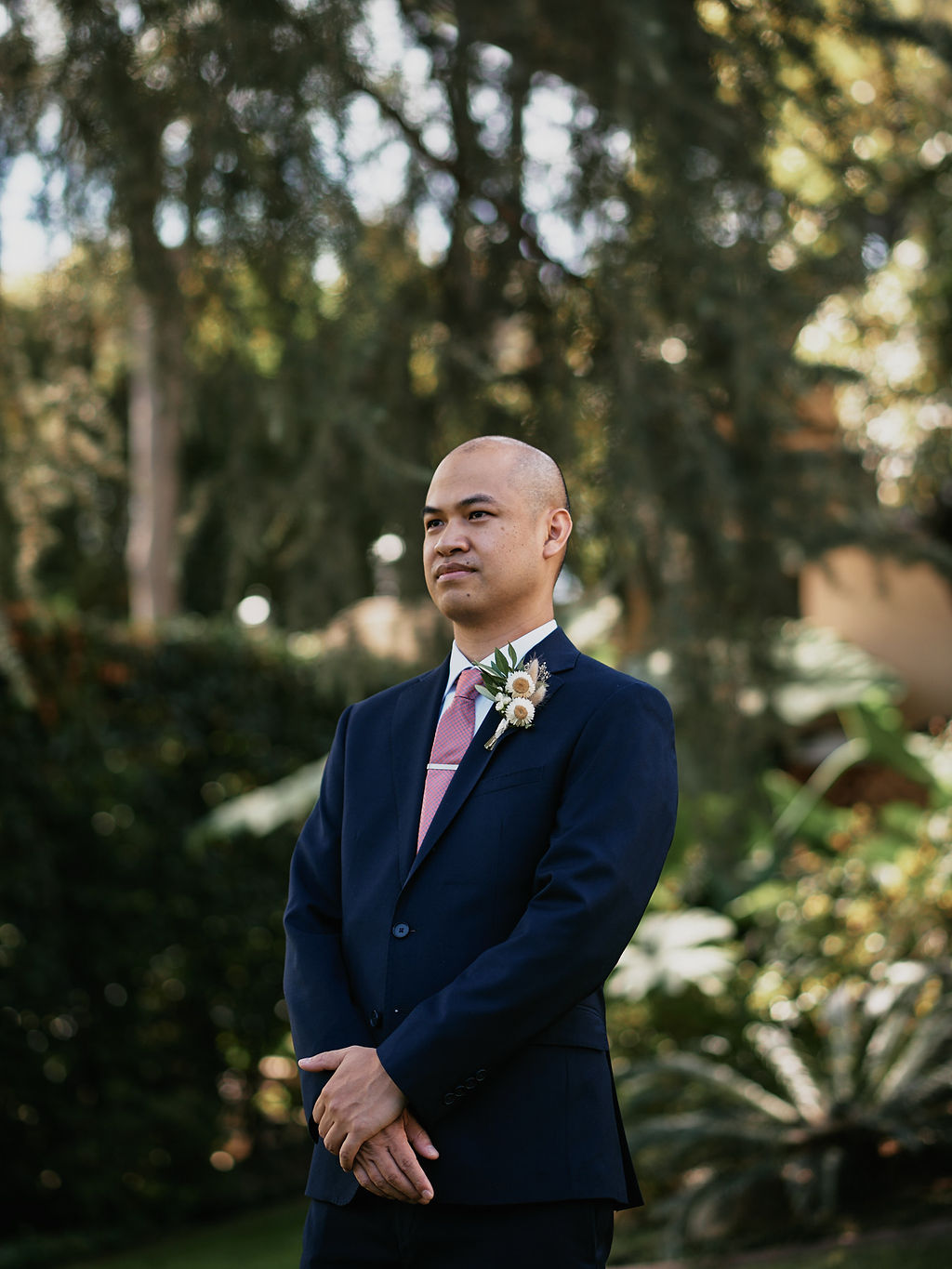 groom in navy suit and pink tie with white flower boutonniere 