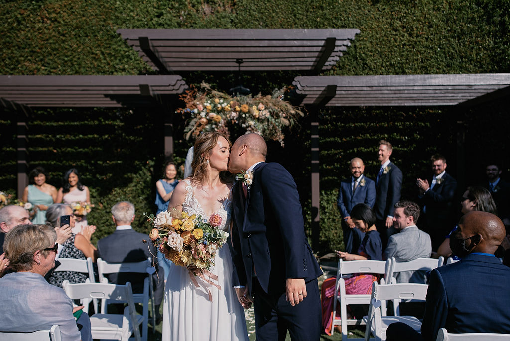 bride and groom kiss during recessional after wedding at Altadena Country Club