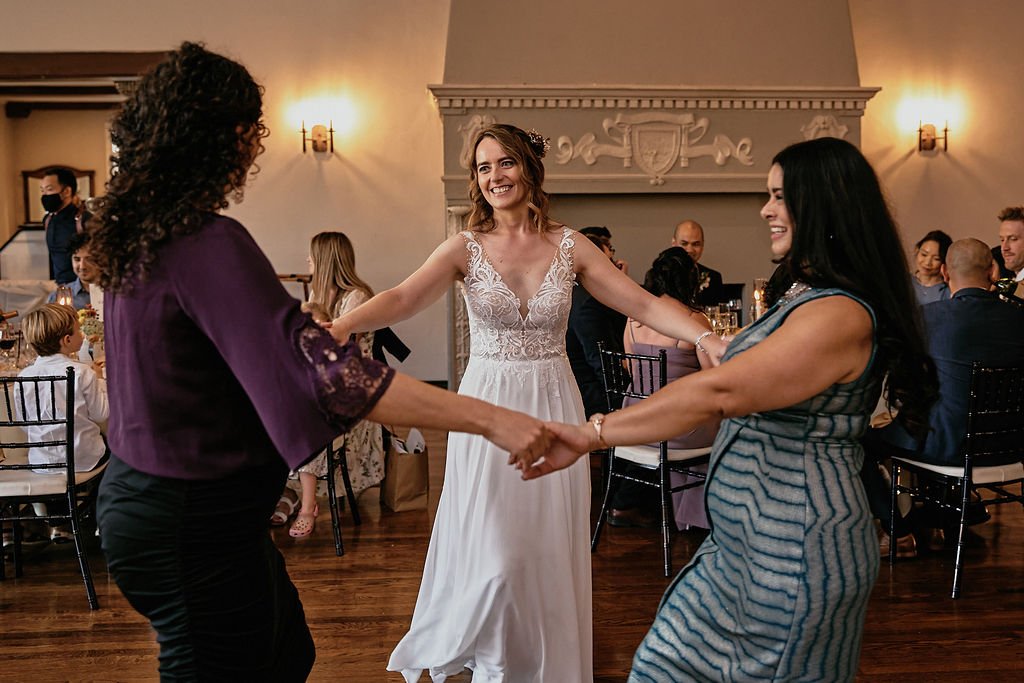 bride holds hands with friends and family while dancing during wedding reception