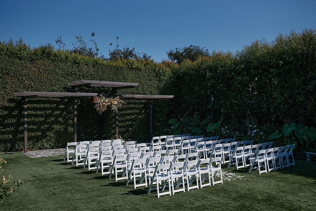 wedding ceremony at Altadena Country Club with white chairs and hanging floral installation at ceremony pergola