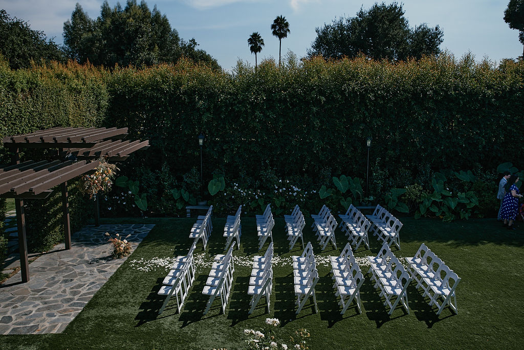 wedding ceremony at Altadena Country Club with white chairs and hanging floral installation at ceremony pergola