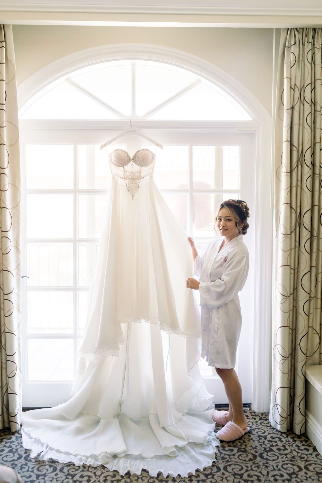 bride stands next to embellished strapless chiffon wedding dress