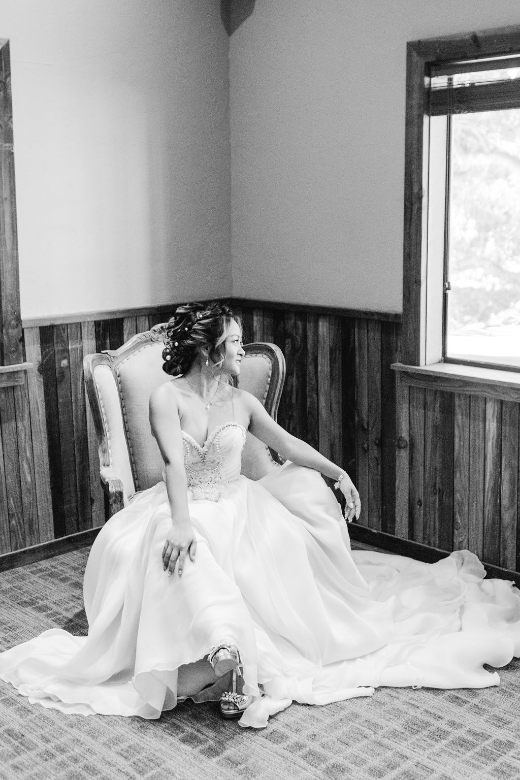 bride in embellished strapless chiffon wedding dress sits on chair