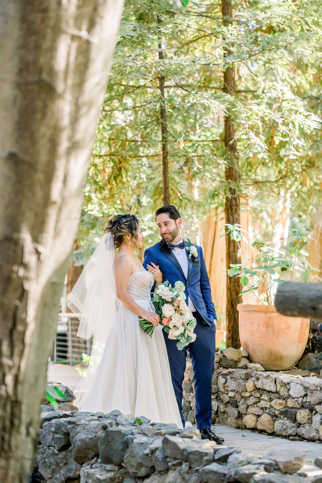 groom with paisley detail bowtie and blue tuxedo has first look with bride in embellished chiffon strapless wedding dress at Calamigos Ranch
