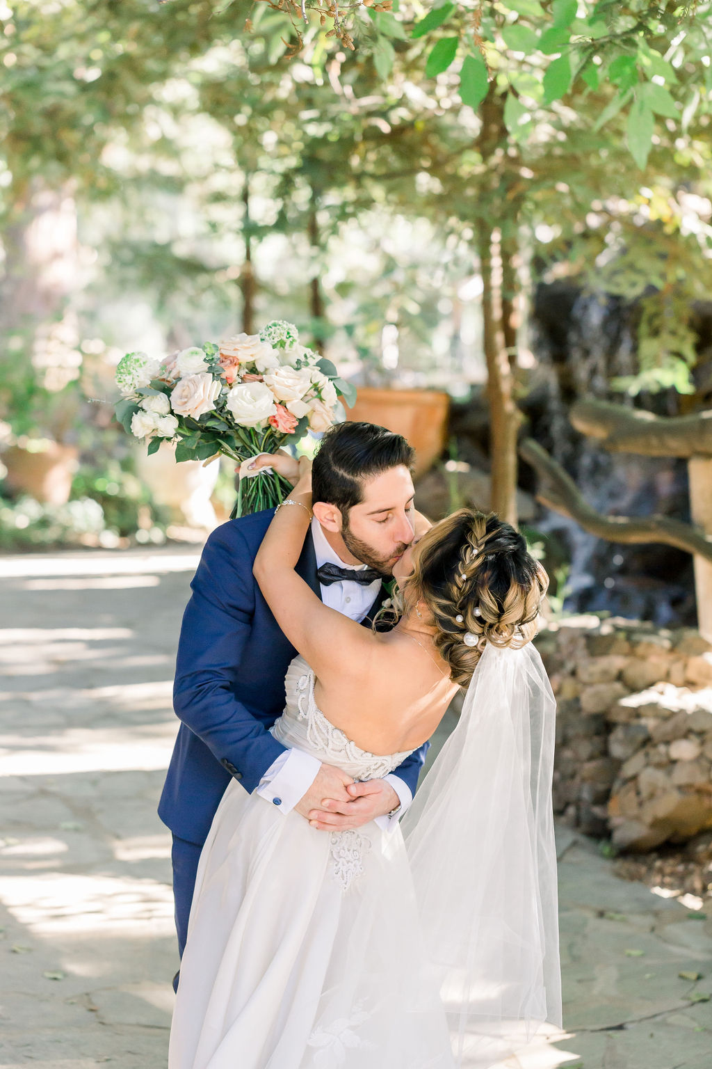 groom with paisley detail bowtie and blue tuxedo has first look with bride in embellished chiffon strapless wedding dress at Calamigos Ranch