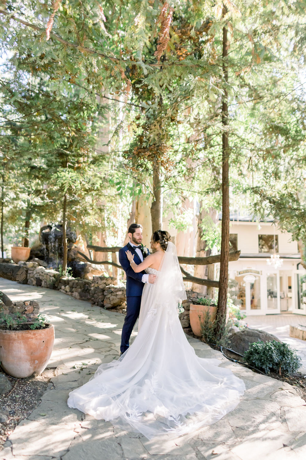 groom with paisley detail bowtie and blue tuxedo stands with bride in embellished chiffon strapless wedding dress at Calamigos Ranch