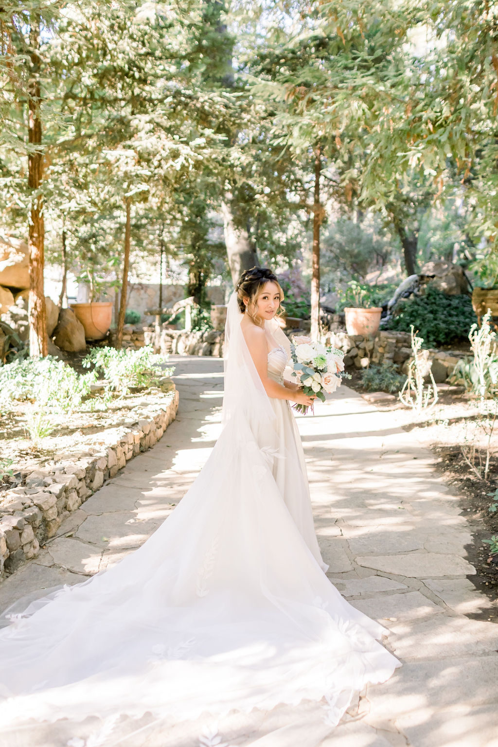 bride in embellished chiffon strapless wedding dress with long train and veil at Calamigos Ranch