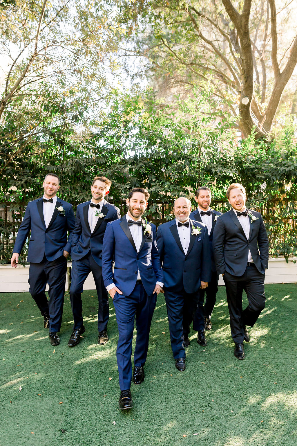 groom with paisley detail bowtie and blue tuxedo stands with groomsmen in blue tuxedo suits