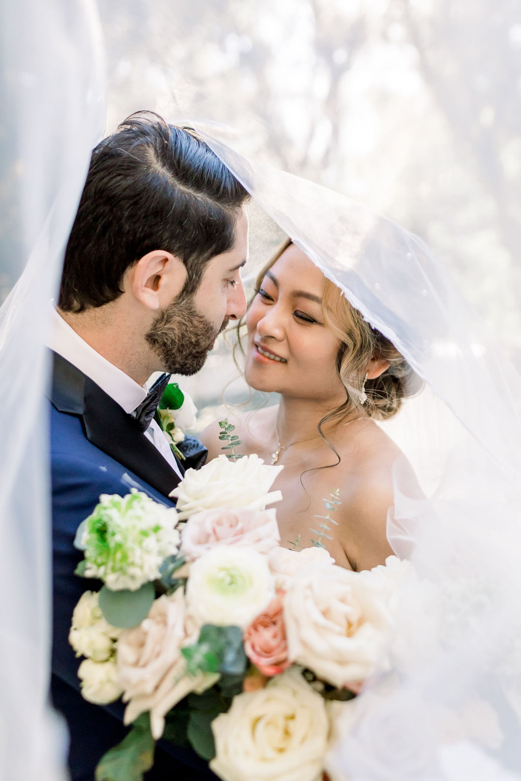 bride and groom take portraits under wedding veil