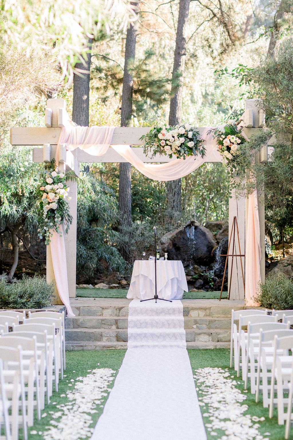 romantic and glamorous wedding ceremony with blush pink chiffon draping the ceremony arch at The Redwood Room at Calamigos Ranch in Malibu 