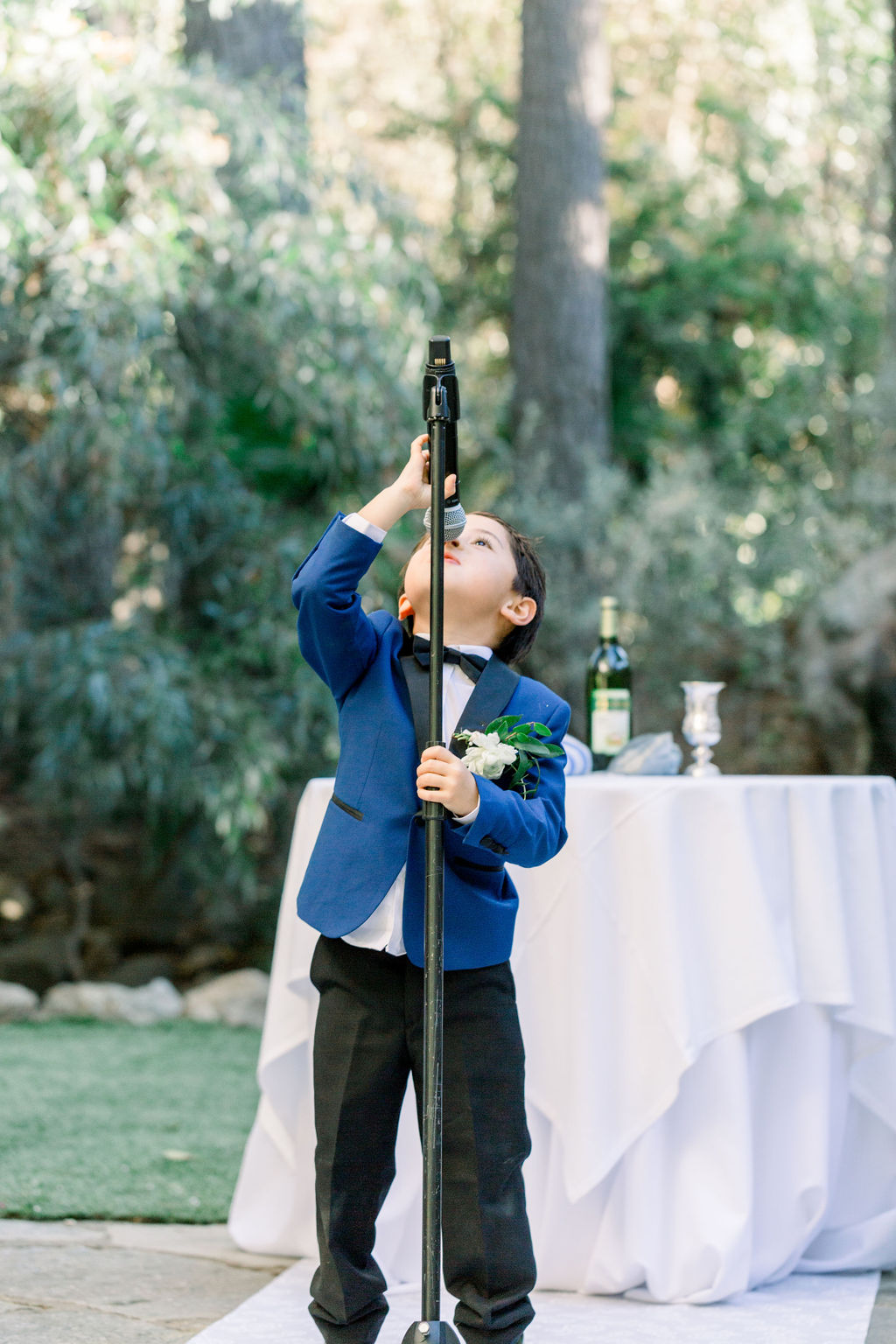 ring bearer in blue suit reaches for microphone