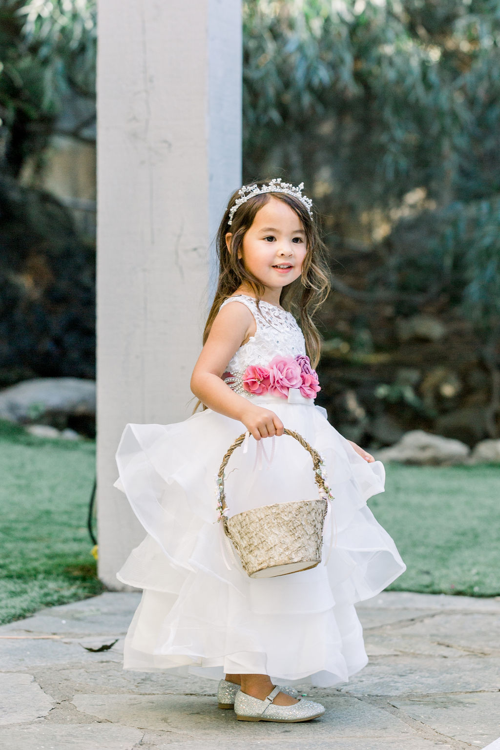 flower girl with white dress and tiara holds flower basket 