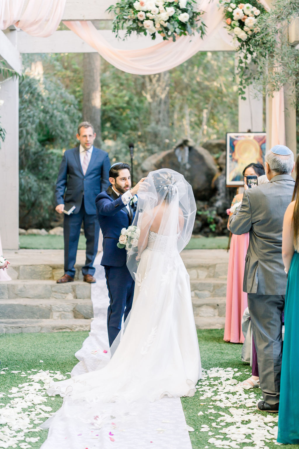 groom lifts bride's veil during romantic and glamorous wedding ceremony at Calamigos Ranch