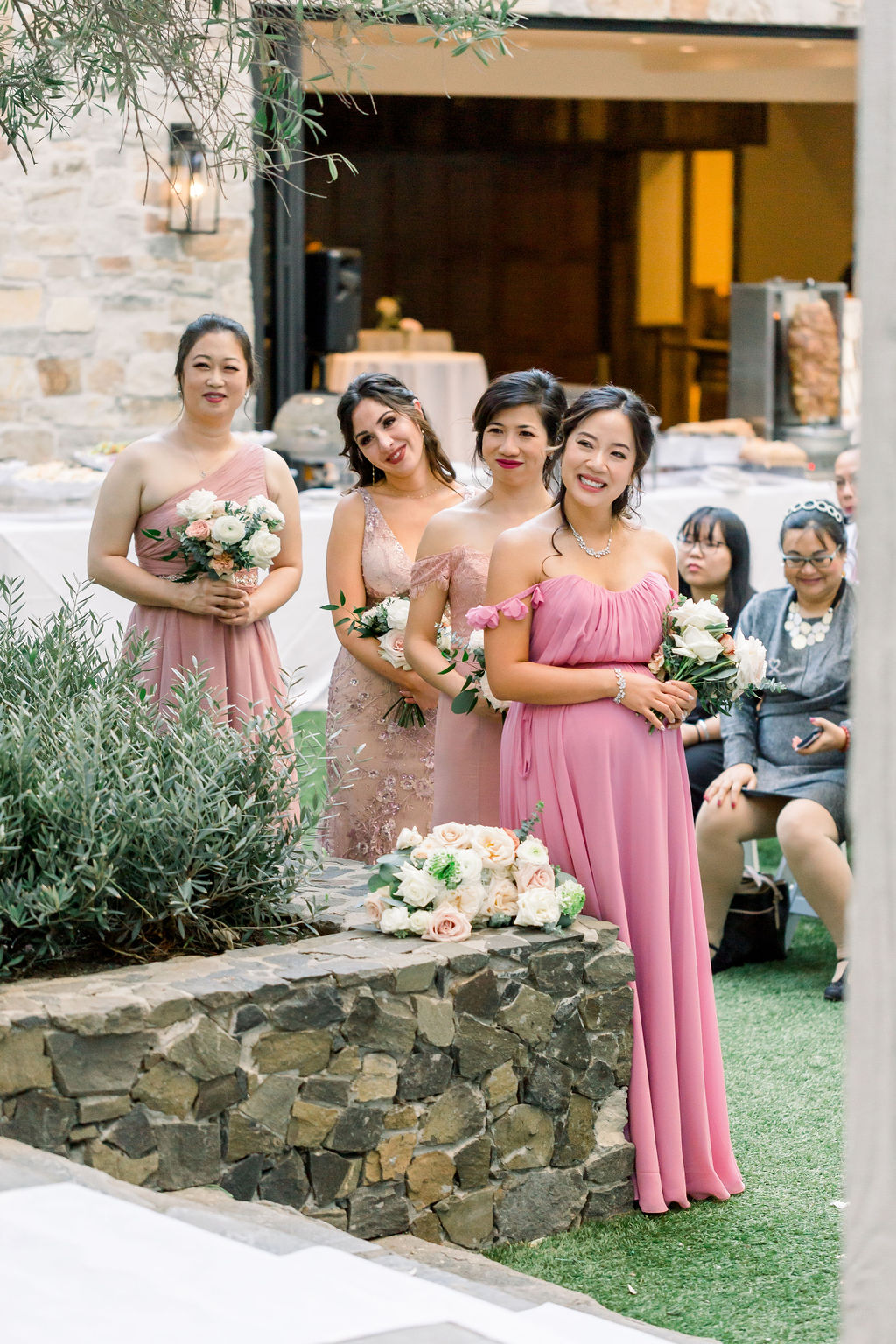 bridesmaids in mix matched pink dresses stand during wedding ceremony at Calamigos Ranch