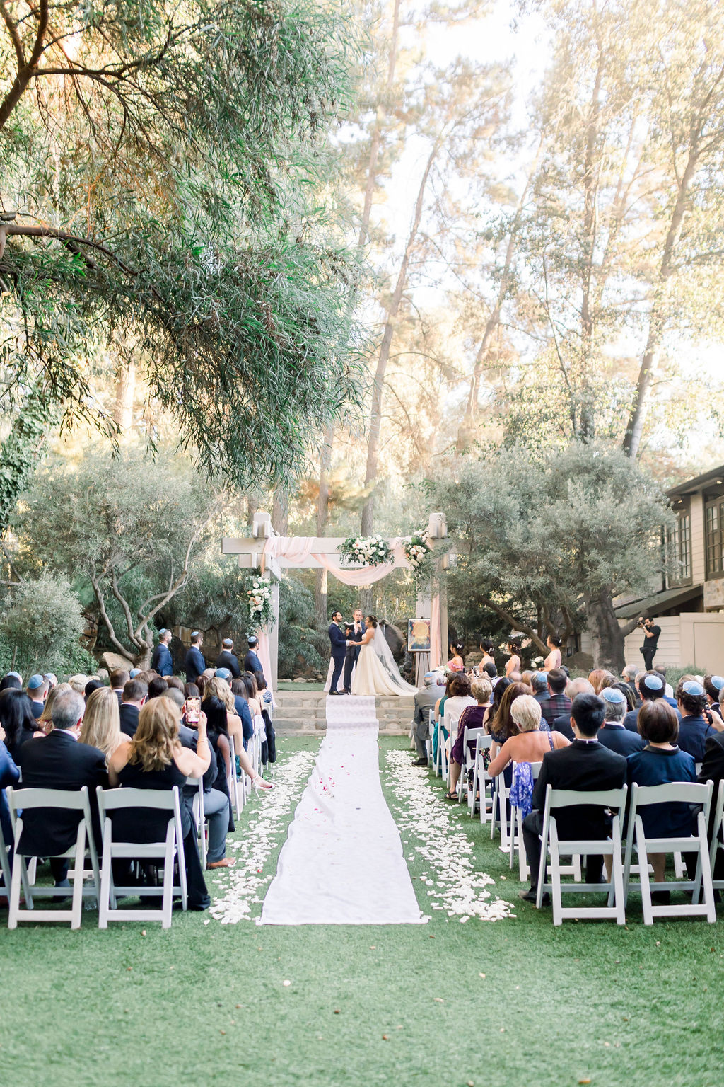 bride and groom hold hands during romantic and glamorous wedding ceremony at Calamigos Ranch
