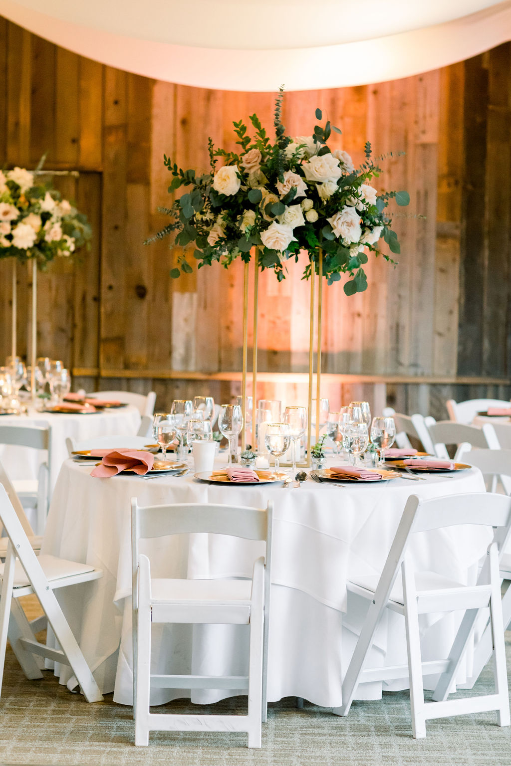 romantic and glamorous wedding reception at the Redwood Room at Calamigos Ranch with pink napkins and tall gold stand floral centerpieces 