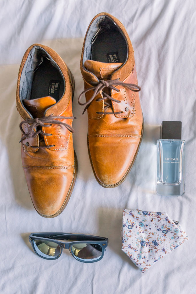 groom detail shot with shoes, sunglasses, floral tie and cologne
