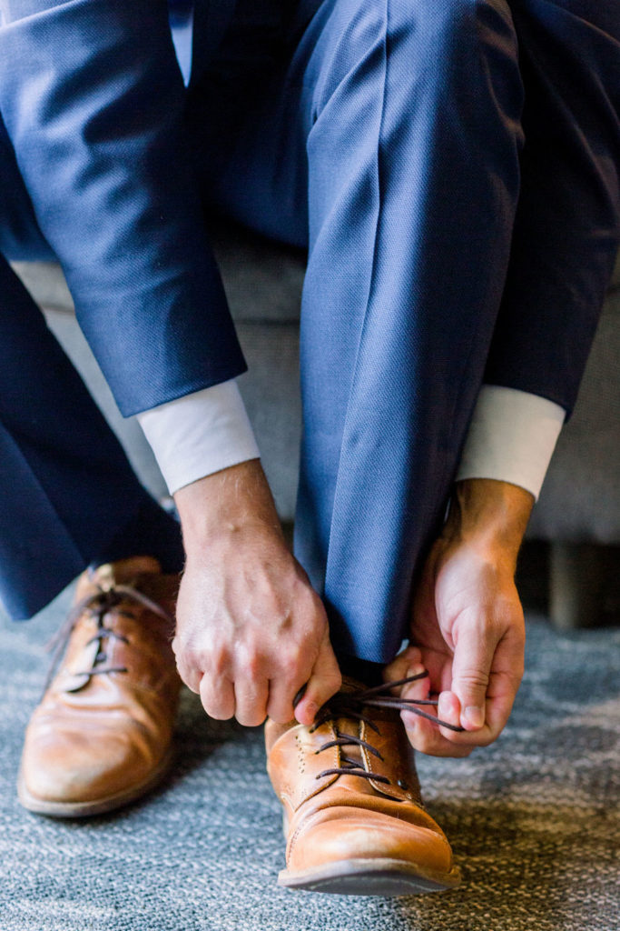 groom tying brown shoes