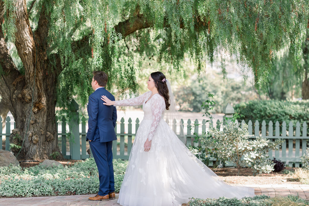 bride in long sleeve wedding dress does first look with groom in blue suit