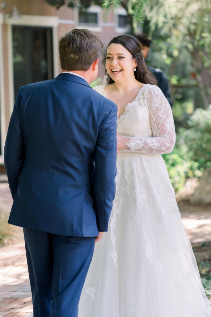 bride in long sleeve wedding dress does first look with groom in blue suit