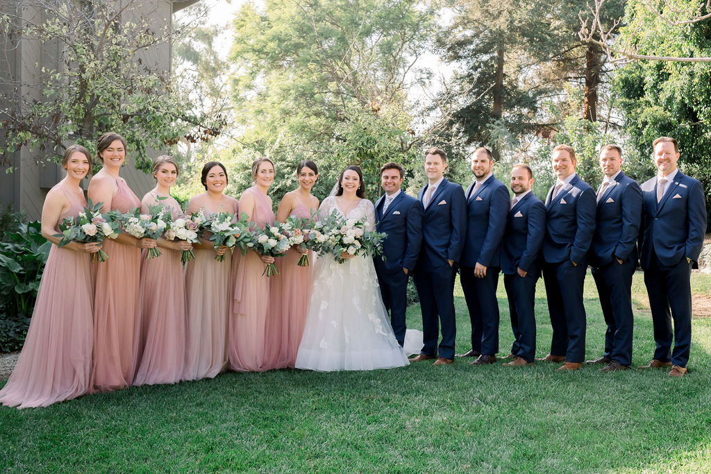 wedding party photo with pink bridesmaid dresses and blue groomsmen suits with floral ties