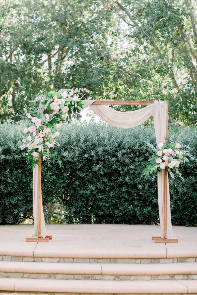 charming wedding ceremony arch at Maravilla Gardens with soft pink chiffon drape and variety of pink florals with eucalyptus 