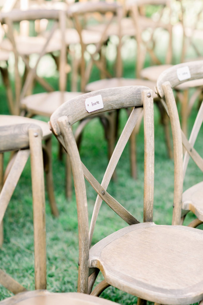 rustic wooden chairs with guests names lined up for charming wedding ceremony at Maravilla Gardens