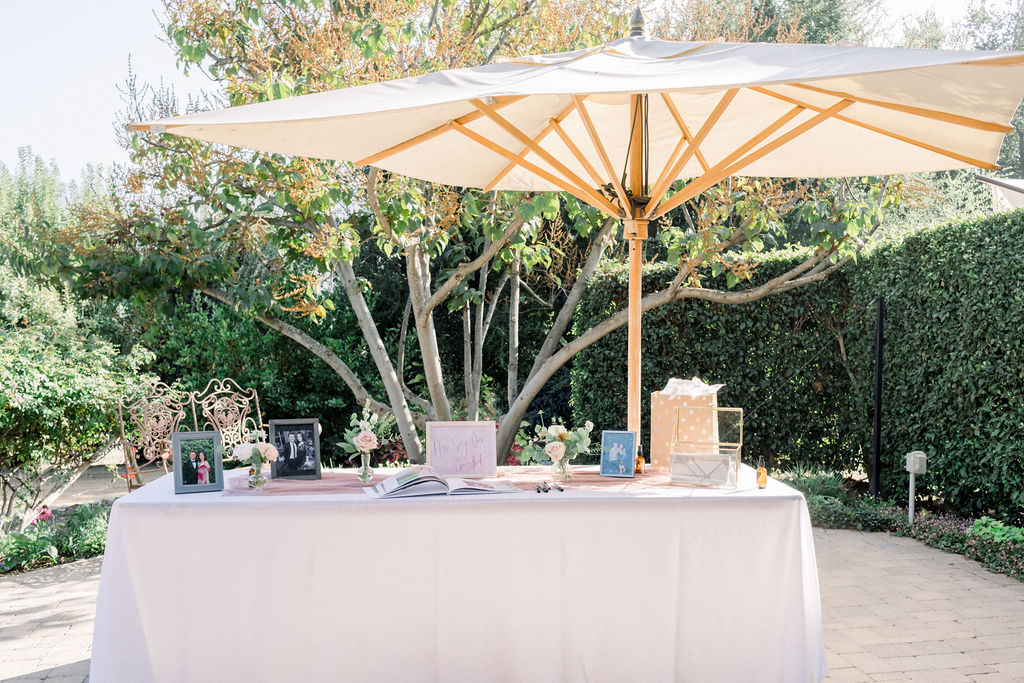 wedding welcome table with photos and card box under an umbrella