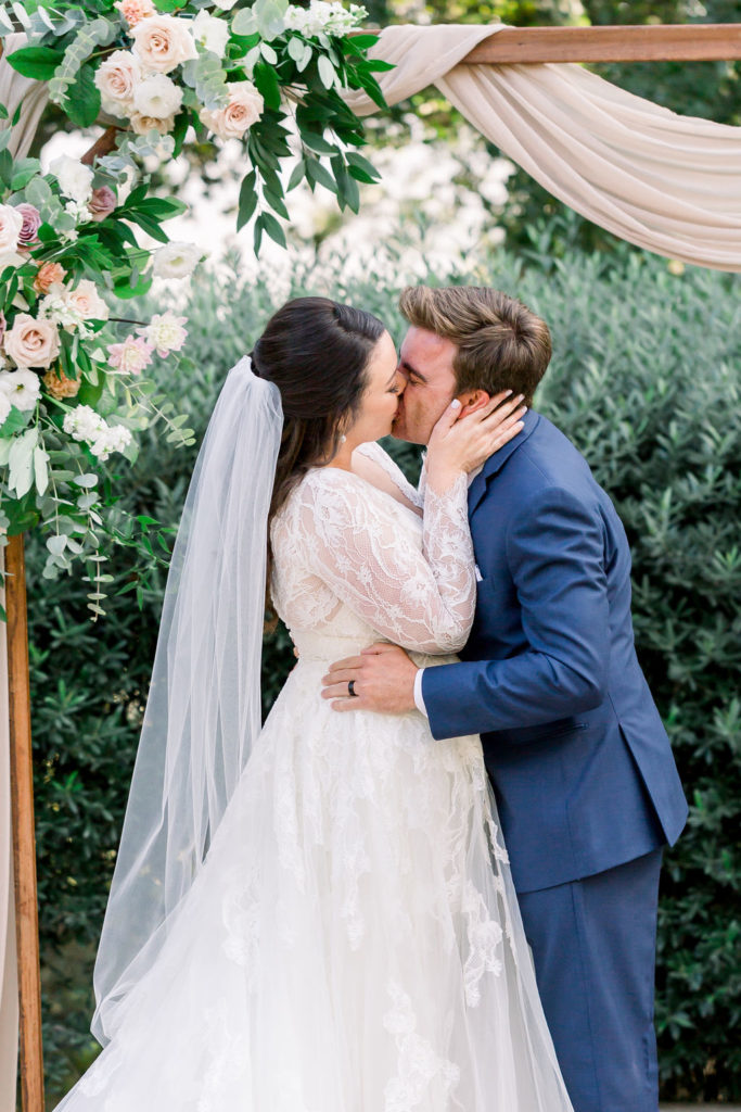 bride and groom first kiss during charming wedding ceremony at Maravilla Gardens 
