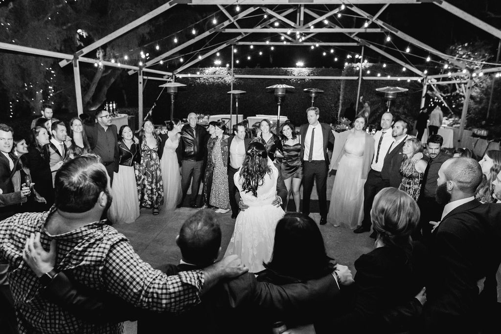 bride and groom dancing together with wedding guests surrounding them