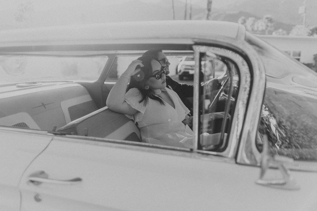 engaged couple poses with white vintage car during engagement photo session in Palm Springs