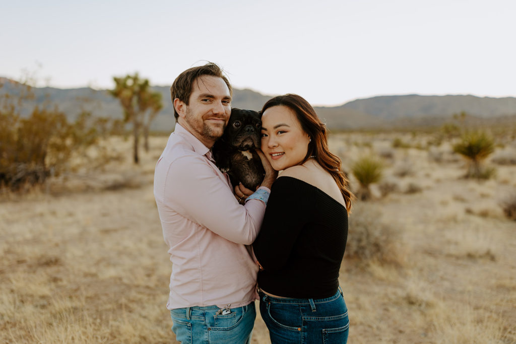 engaged couple pose in Palm Springs desert with their dog for their engagement photos