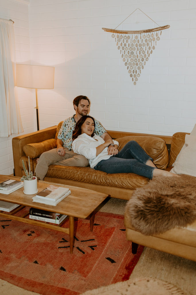 engaged couple sitting comfortably in air bnb during engagement photo session in Palm Springs