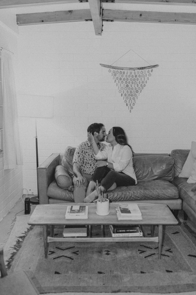 engaged couple sitting comfortably in living room during engagement photo session in Palm Springs