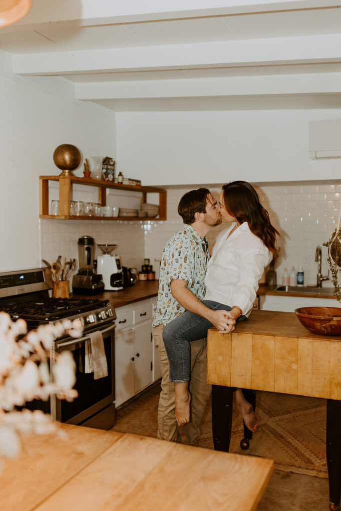 engaged couple kissing in kitchen during engagement photo session in Palm Springs