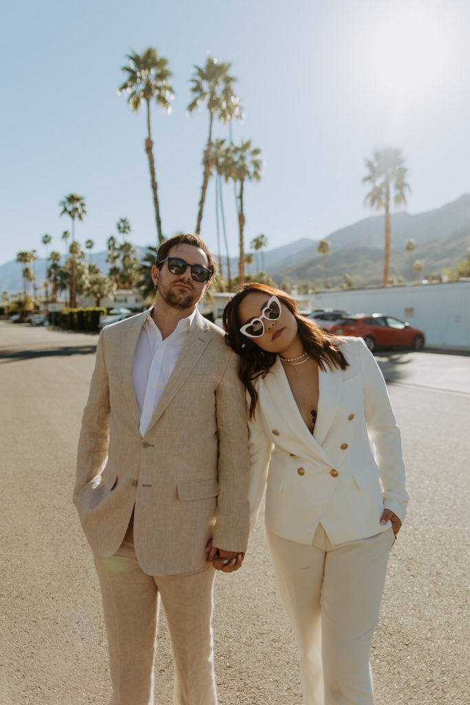 engaged couple wearing neutral matching power suits pose in mid century hotel in Palm Springs for engagement photo session