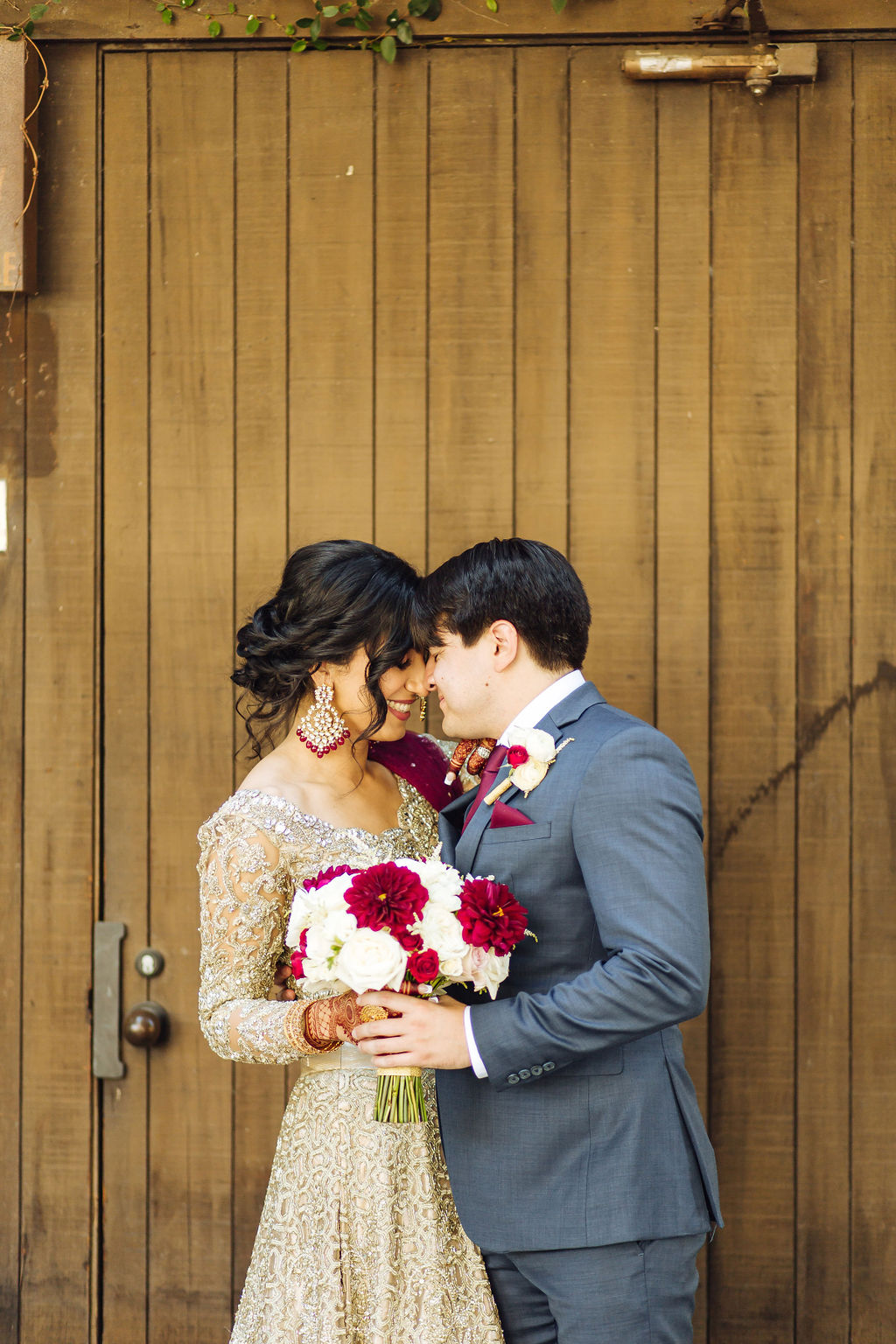 bride wearing embellished golden wedding saree and groom in dark grey suit with maroon at Los Angeles River and Garden Center