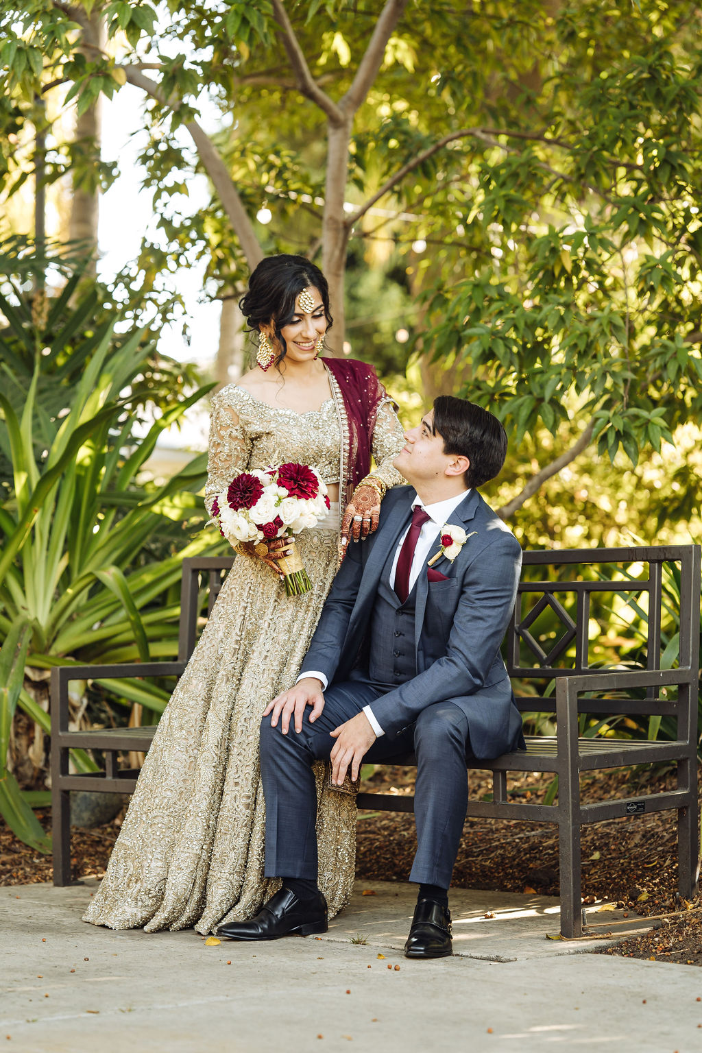 bride wearing embellished golden wedding saree and groom in dark grey suit with maroon at Los Angeles River and Garden Center