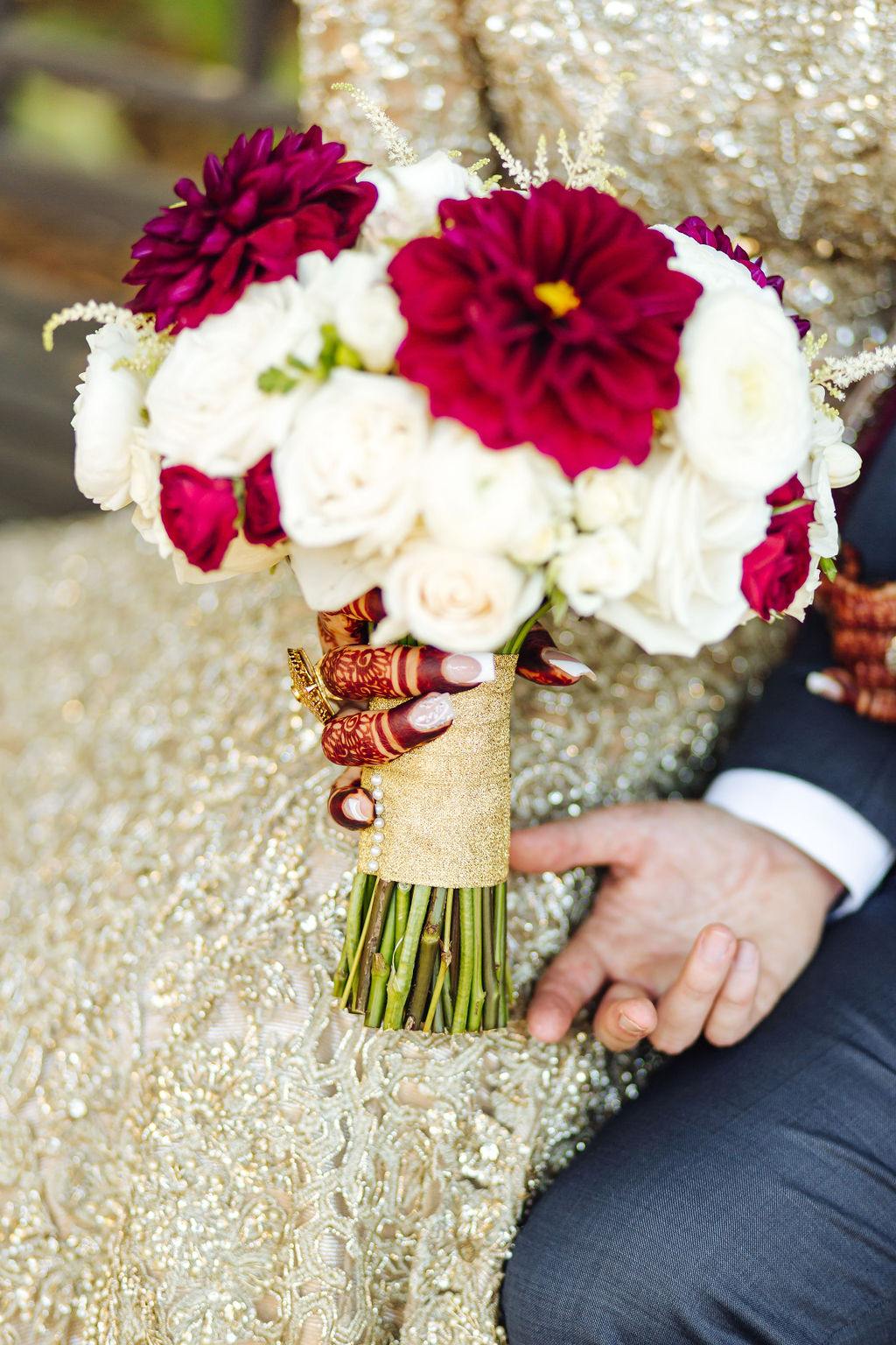 bridal bouquet with maroon and white flowers tied with a gold ribbon