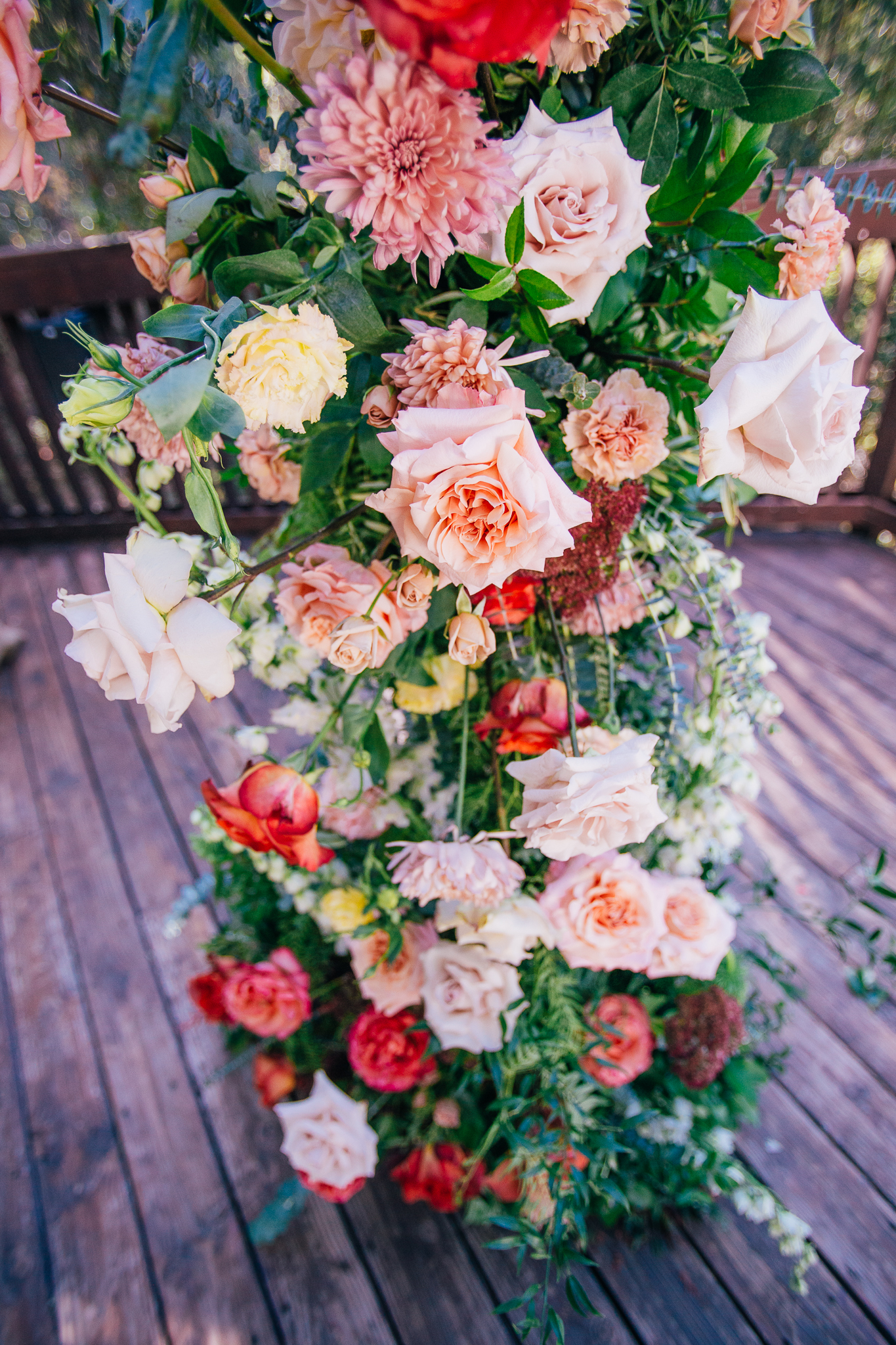 wedding ceremony arch florals in a mix of pink, red, yellow, orange, white and greenery