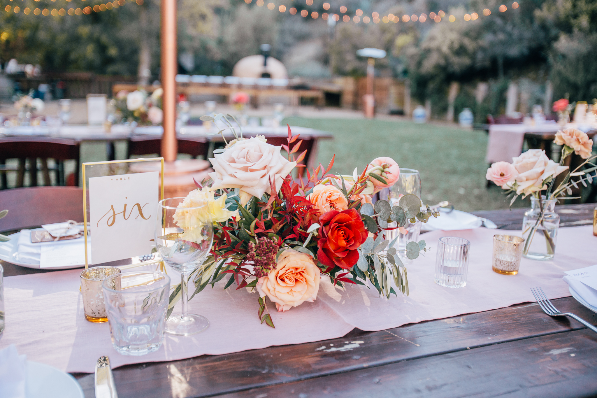bright and vibrant wedding reception at the 1909 with wooden farmhouse tables, wood chairs and colorful floral centerpieces