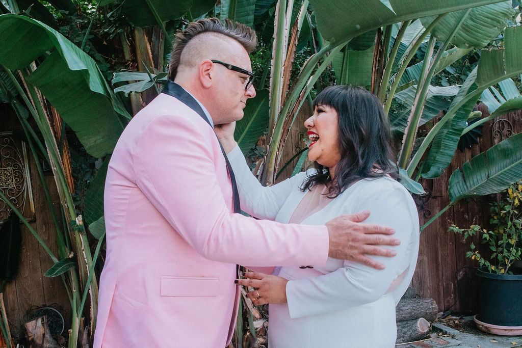 bride in long sleeve deep v-neck wedding dress has first look with groom in pink suit jacket and houndstooth shoes 