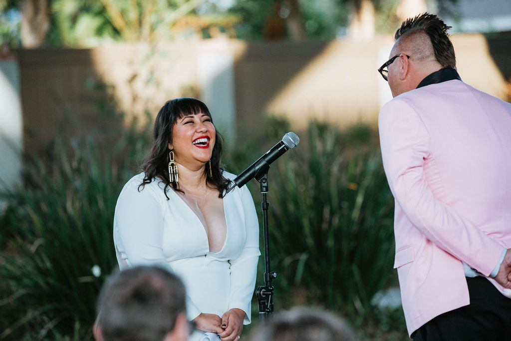 bride in long sleeve wedding dress laughs at groom during wedding ceremony